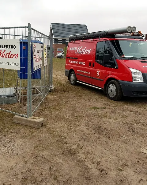 Bedrijfsbus van Elektro Kusters bij een bouwplaats met een bouwbord van Elektro Kusters